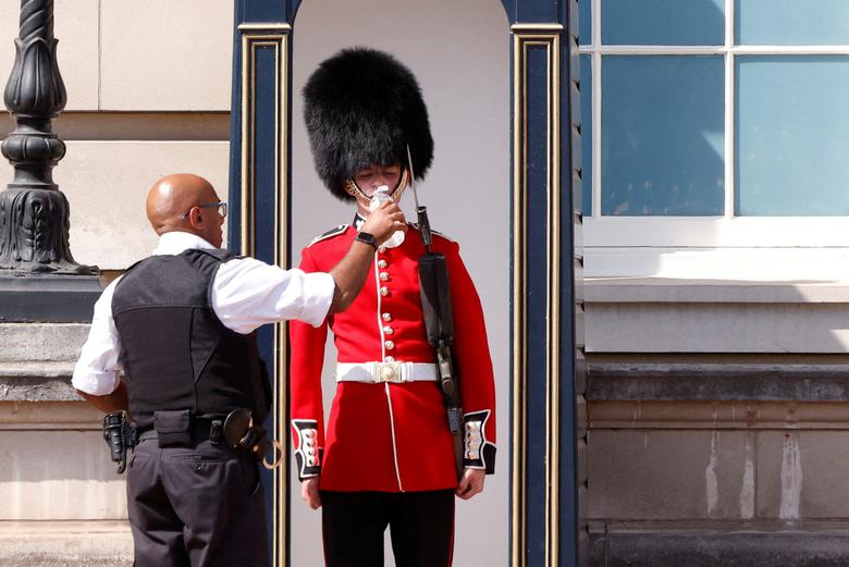 نوشاندن آب به یکی از نگهبانان ملکه در موج گرما، کاخ باکینگهام، لندن، انگلستان